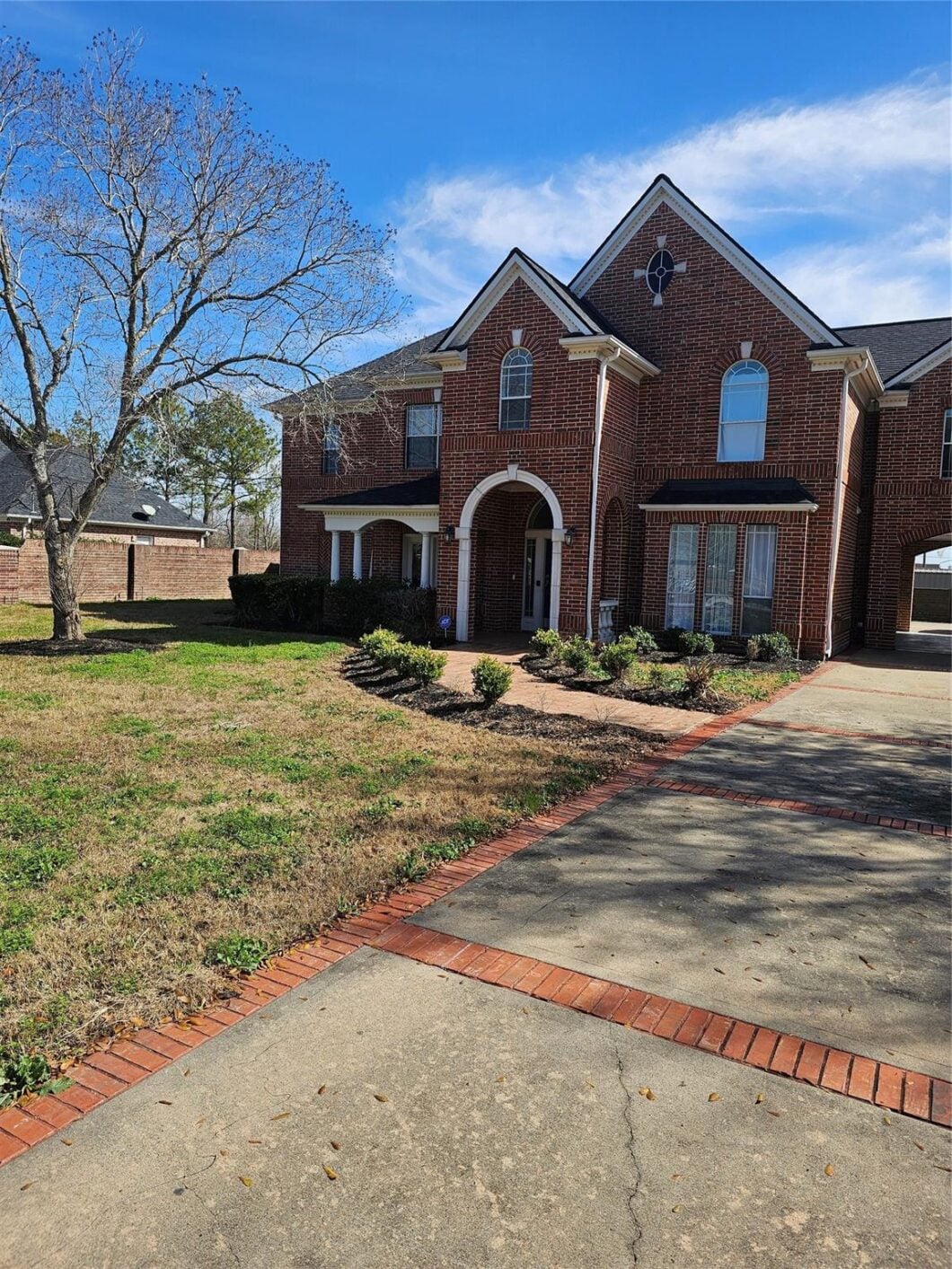 Brick residential home at 1211 Lark Ln, Richmond, featuring a landscaped front yard, arched entryway, and large windows under a clear blue sky.