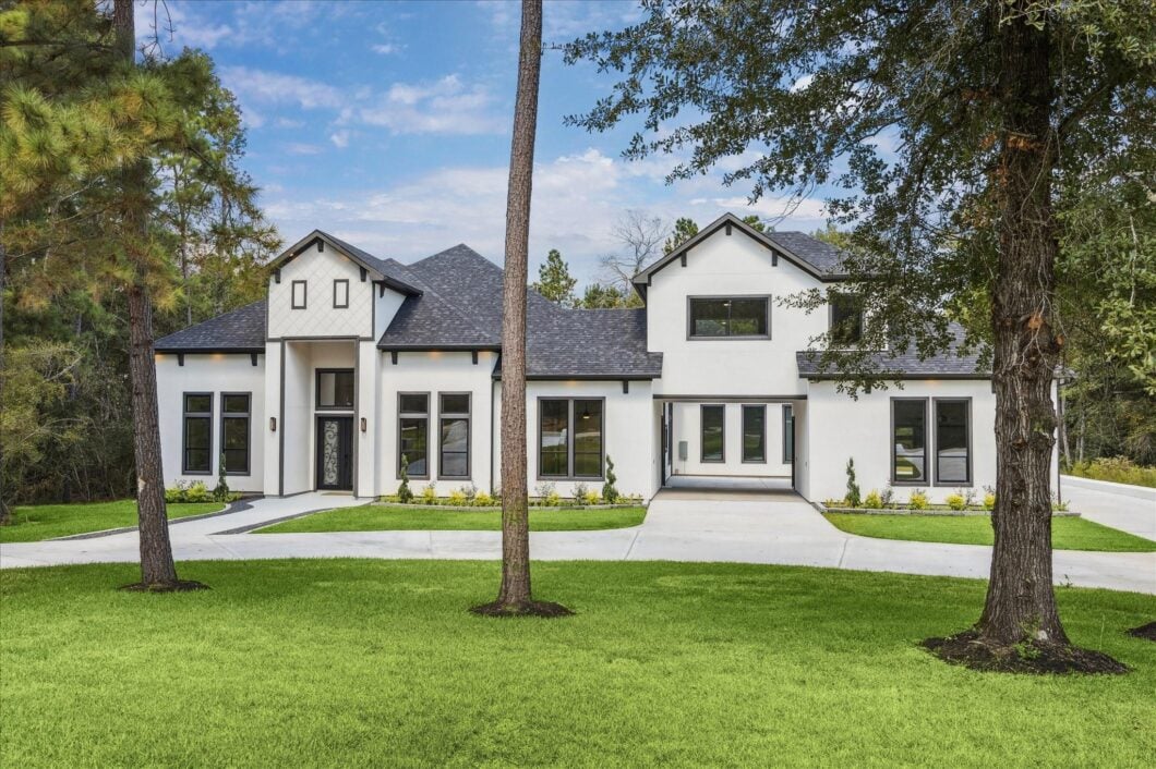 Exquisite modern residential home in High Meadow Estates, featuring a sleek exterior design, manicured lawn, and spacious driveway surrounded by trees.